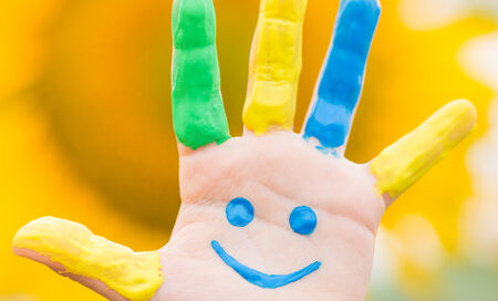 38261565 - happy kid with smiley on hand against spring yellow sunflower background